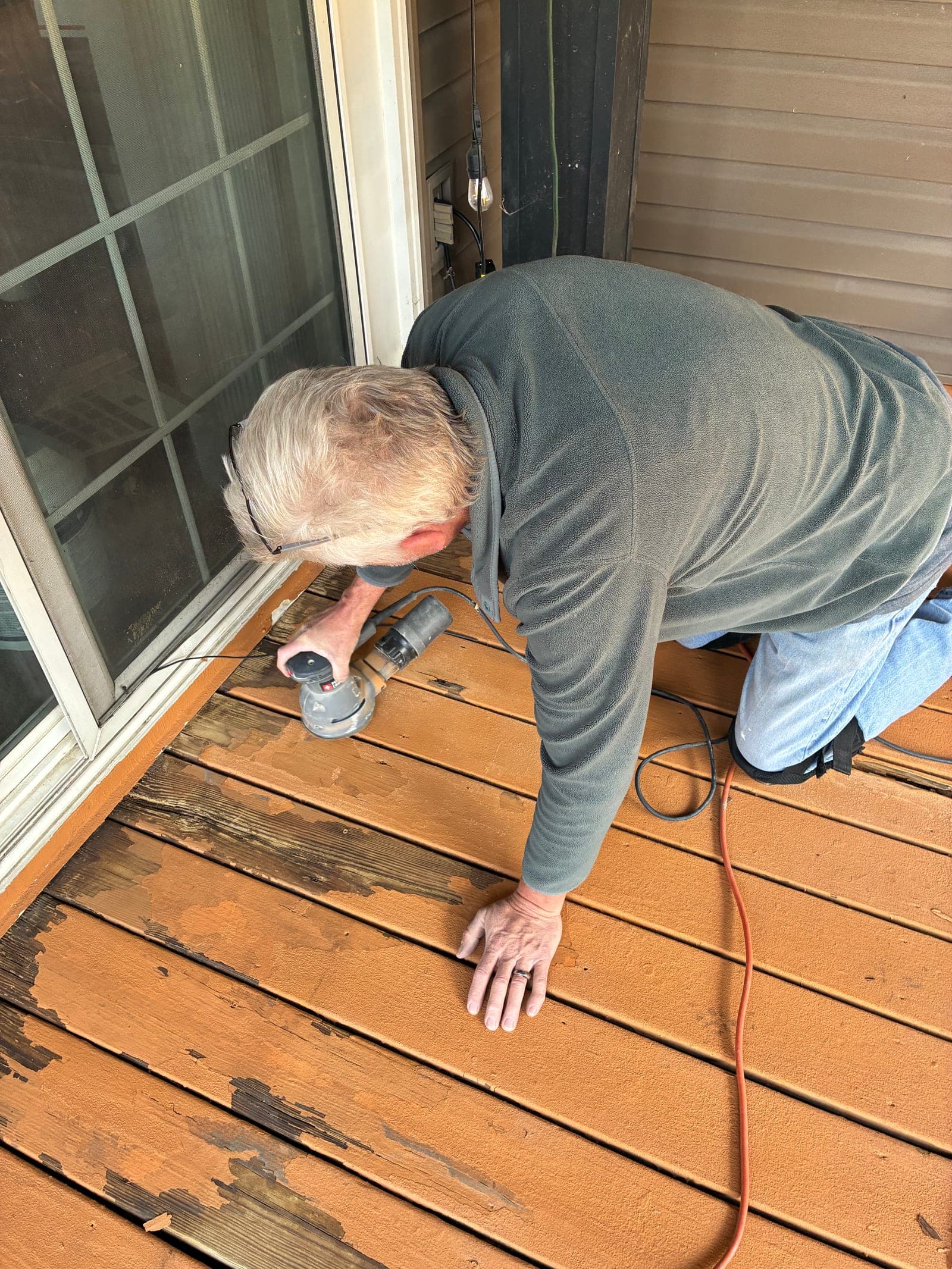 Jeff sanding worn, peeling deck boards with an orbital sander before refinishing