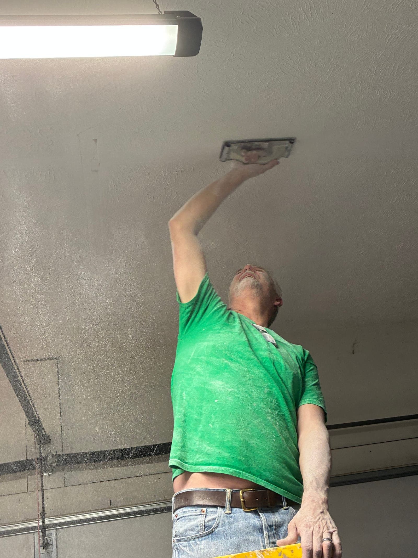Jeff smoothing texture onto a garage ceiling patch with a hand trowel