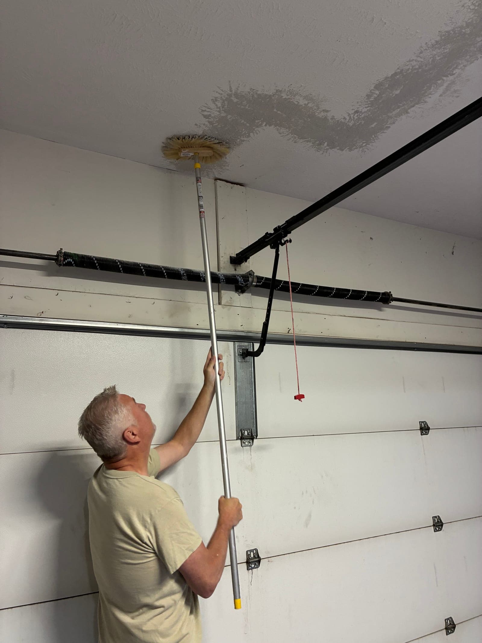 Jeff scrubbing down the garage ceiling near the door track as part of the job