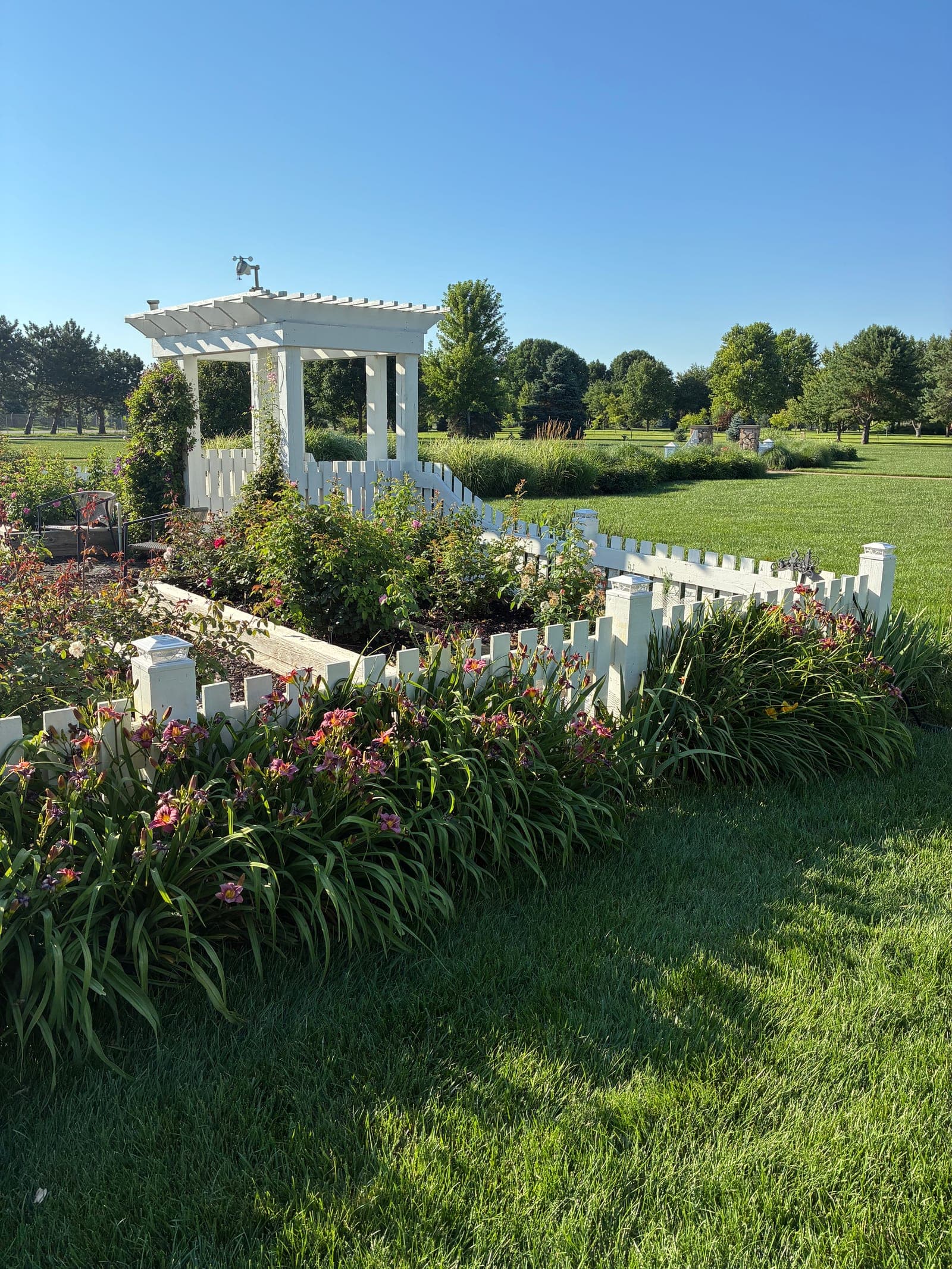 Wide view of the white picket fence and garden with the new finial installed